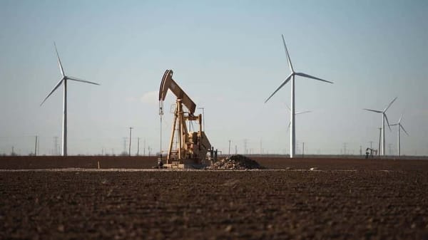 Un Derrick de pétrole et des éoliennes.